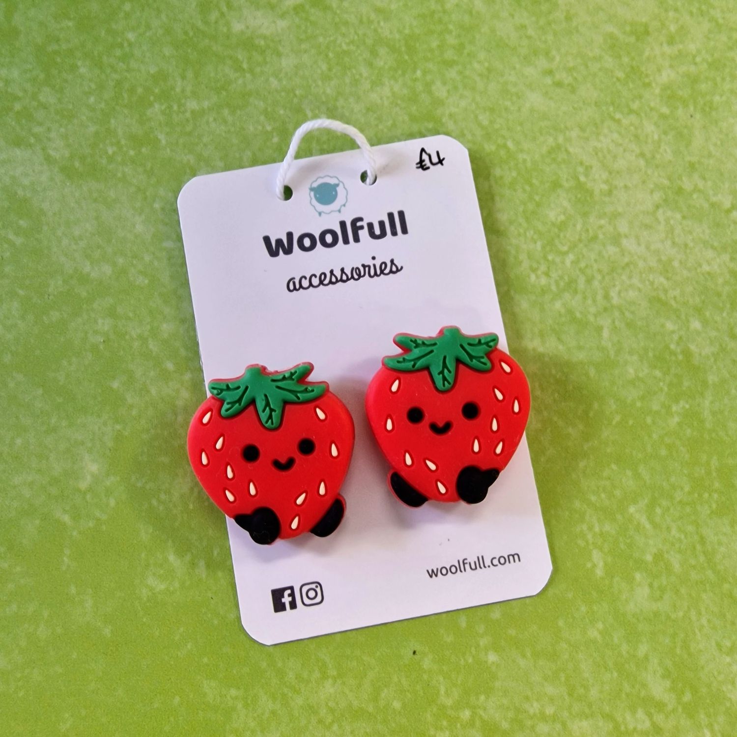 A green background with a pair of strawberry shaped point protectors mounted on a white card.