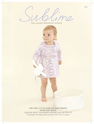 A baby is wearing a knitted dress in a variegated purple yarn.