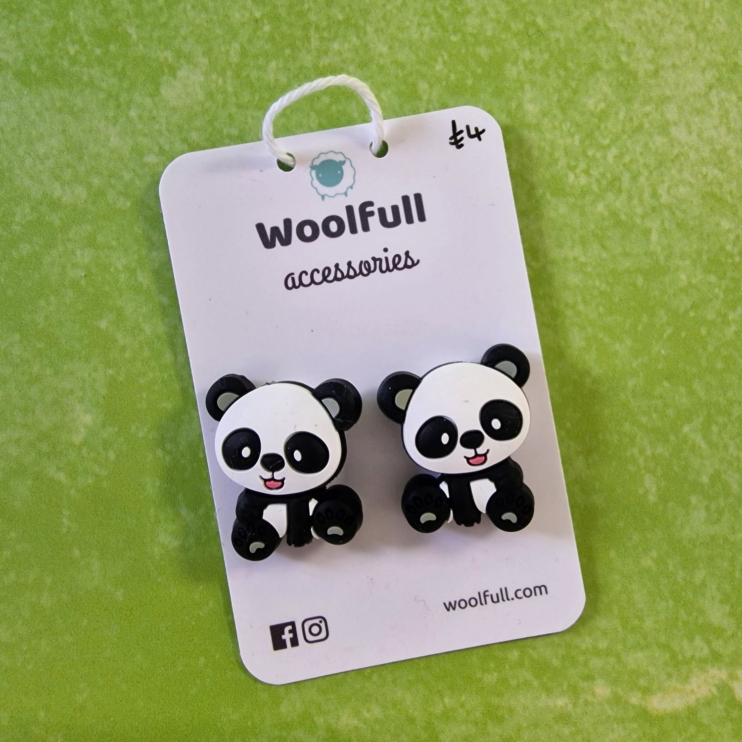 A green background with a pair of panda shaped point protectors mounted on a white card.
