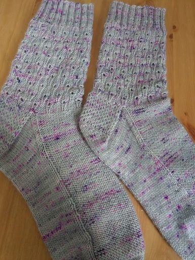 A pair of knitted socks in grey with small purple flecks.