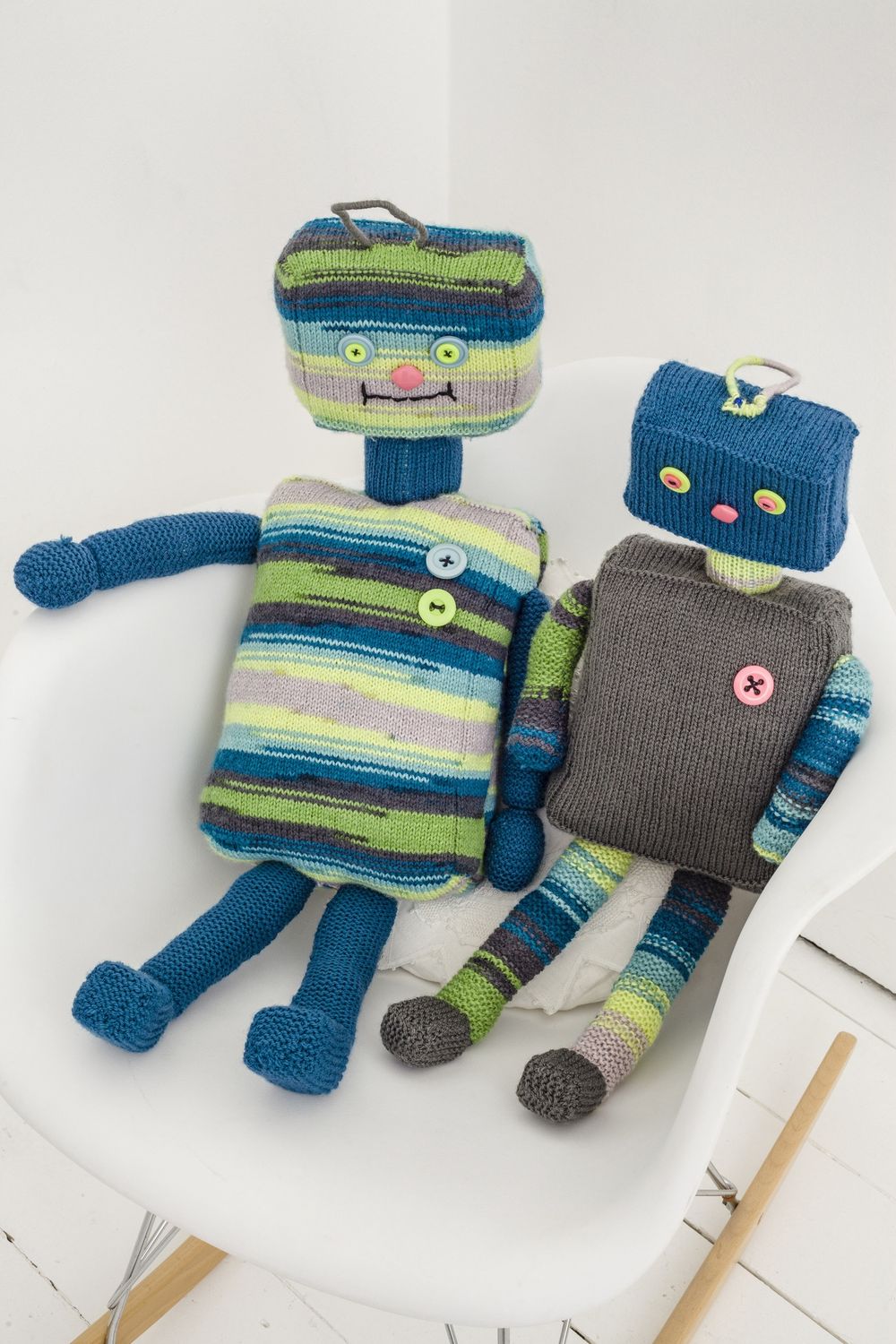 2 knitted robot toys in blue, green and grey.