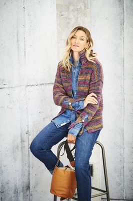 A woman is wearing a knitted cardigan in a variegated dark purple yarn.