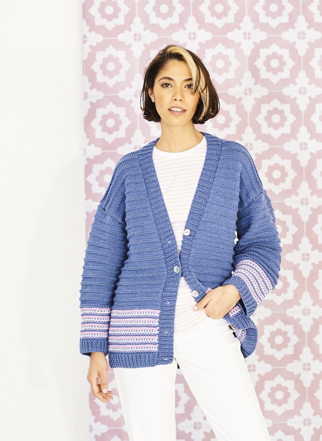 A woman is wearing a blue knitted cardigan with a few pale pink stripes.