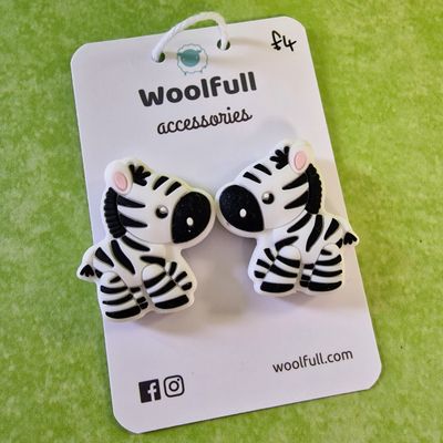A green background with a pair of zebra shaped point protectors mounted on a white card.