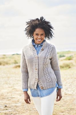 A woman is wearing a beige knitted cardigan with cable on one side.