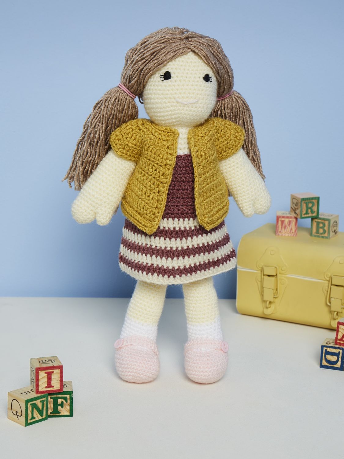 A crocheted doll wearing crocheted clothing.