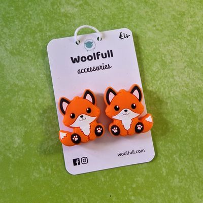 A green background with a pair of fox shaped point protectors mounted on a white card.