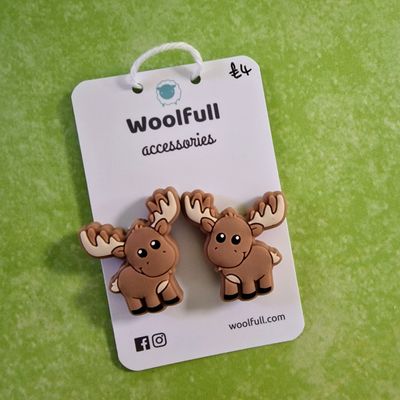 A green background with a pair of moose shaped point protectors mounted on a white card.