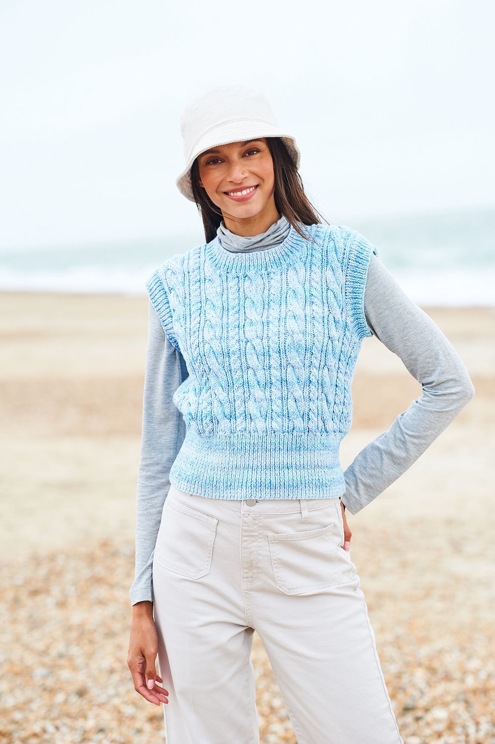 A woman is wearing a knitted tank top in shades of blue.