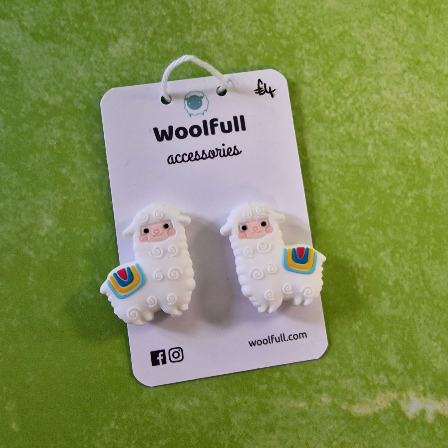 A green background with a pair of alpaca shaped point protectors mounted on a white card.