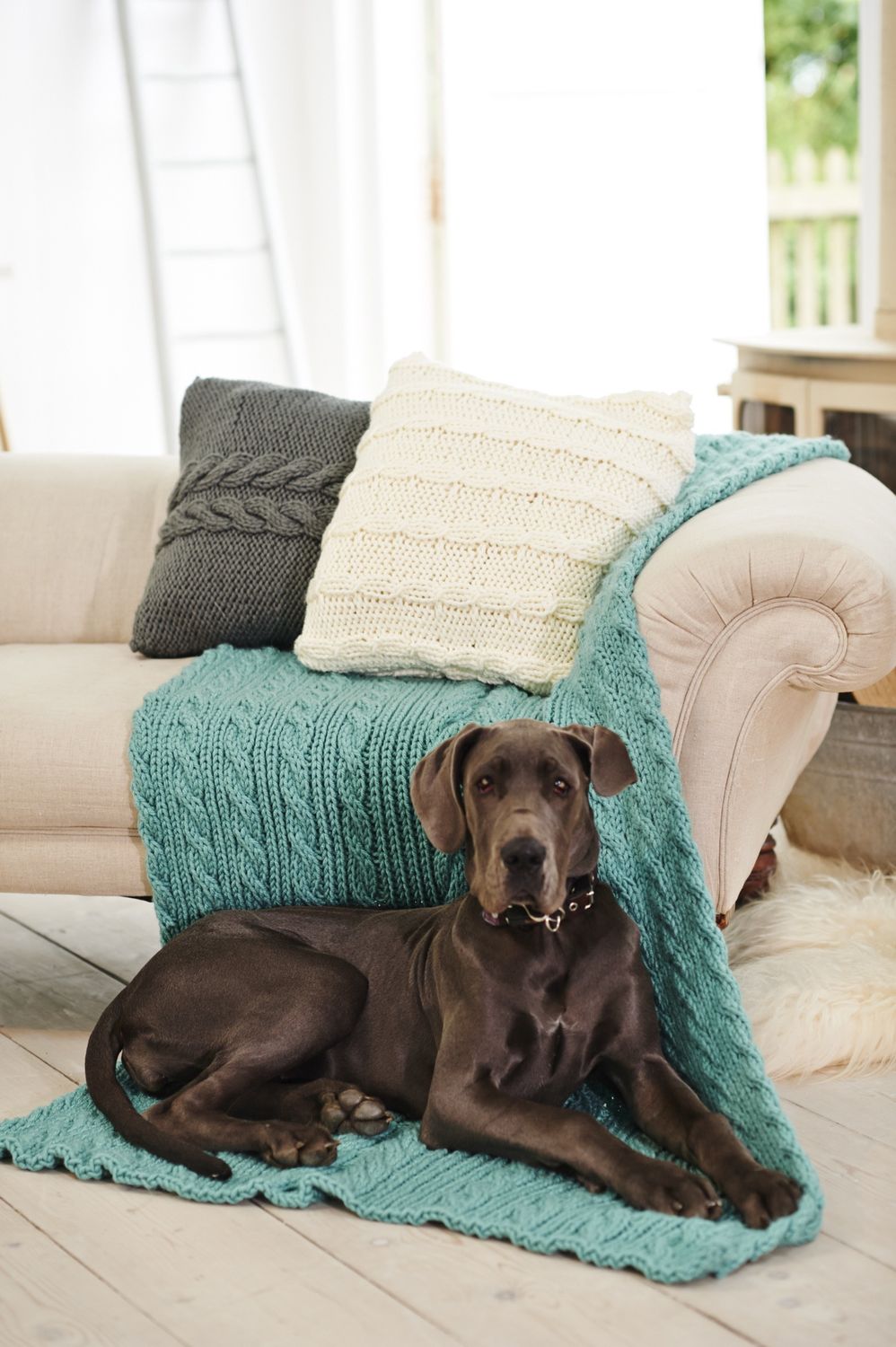 2 knitted cushions and a knitted blanket in grey, cream and blue.