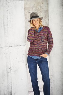 A woman is wearing a knitted sweater in a variegated dark purple and brown yarn.