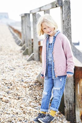 A girl is wearing a pale pink knitted cardigan.
