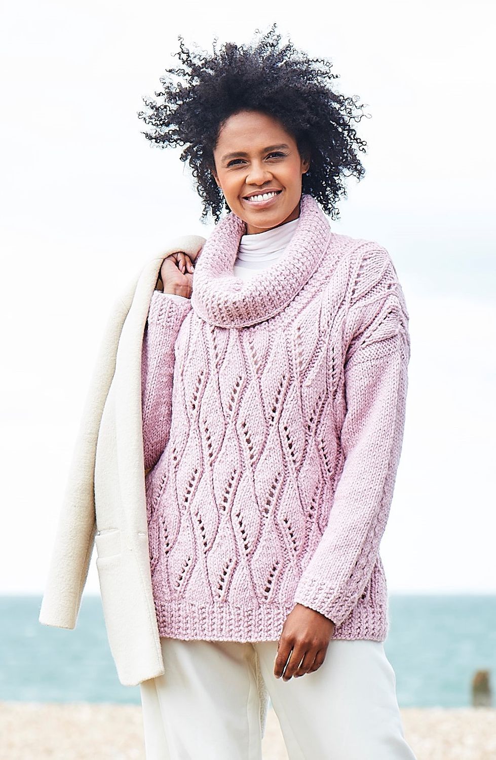 A woman is wearing a pink lacy knitted sweater.