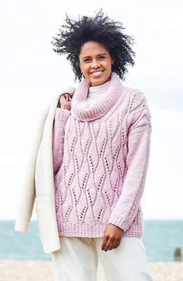 A woman is wearing a pink lacy knitted sweater.