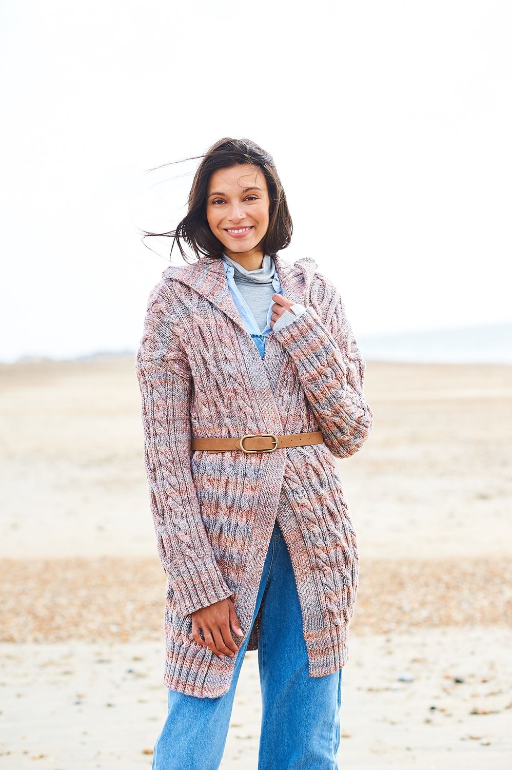 A woman is wearing a knitted jacket in shades of blue and brown.