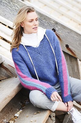 A woman is wearing a blue knitted sweater with pink stripes on the sleeves.