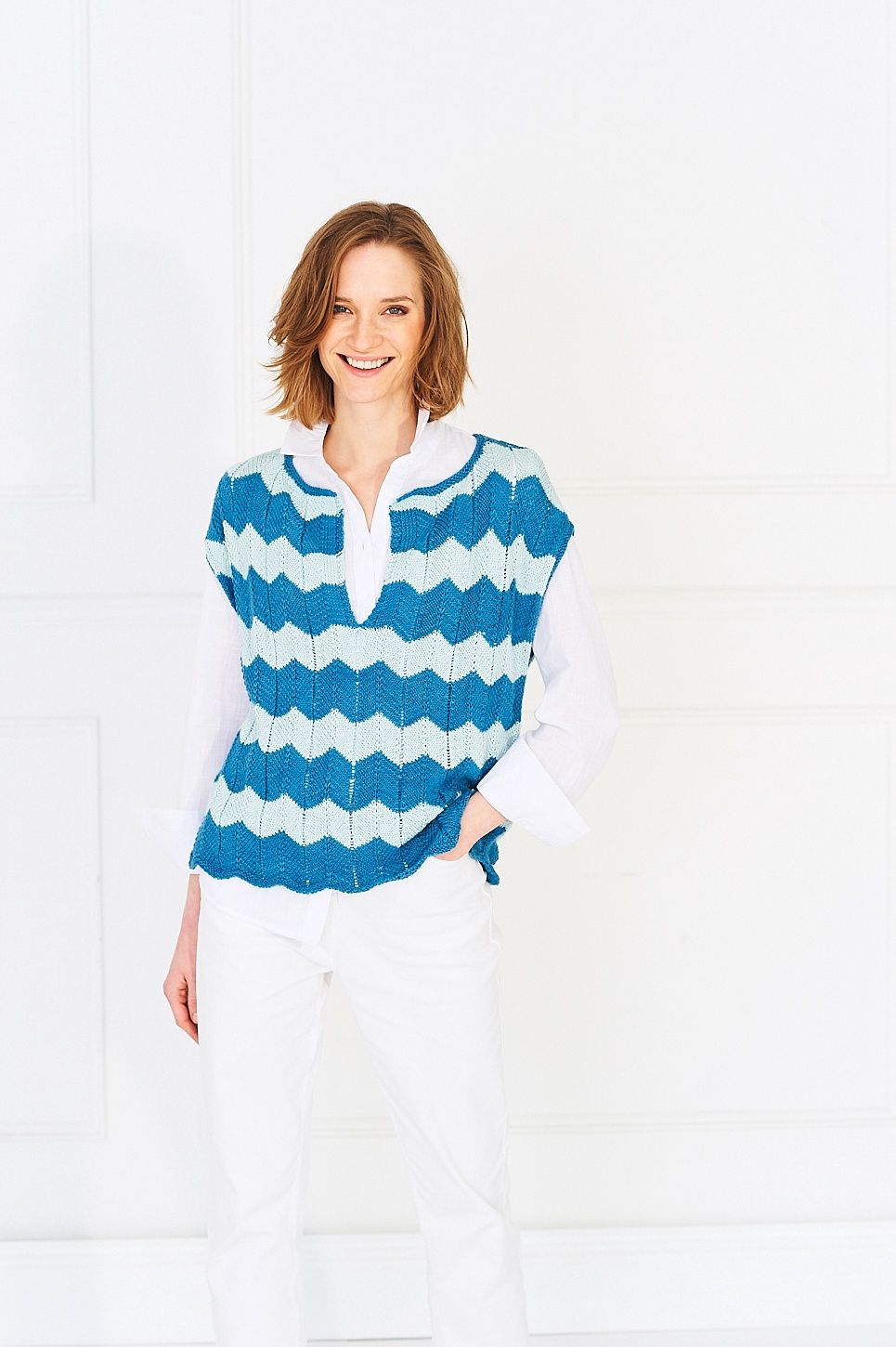 A woman is wearing a knitted ripple top in shades of blue.