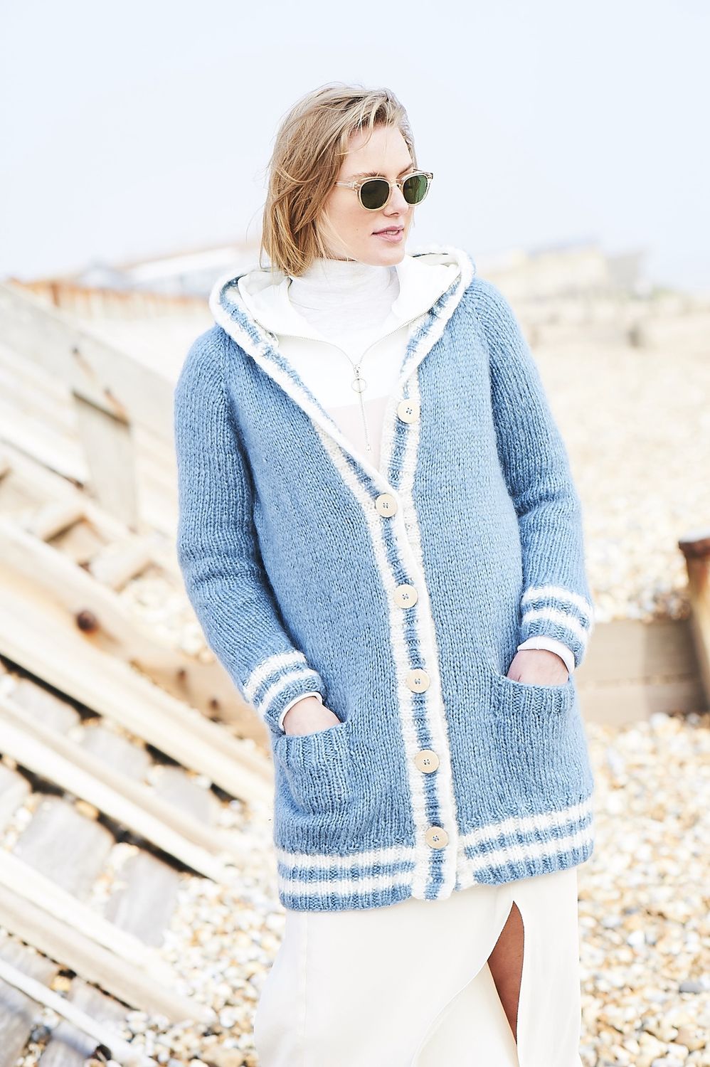 A woman is wearing a light blue knitted cardigan.