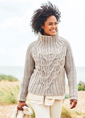 A woman is wearing a beige cable knit sweater.