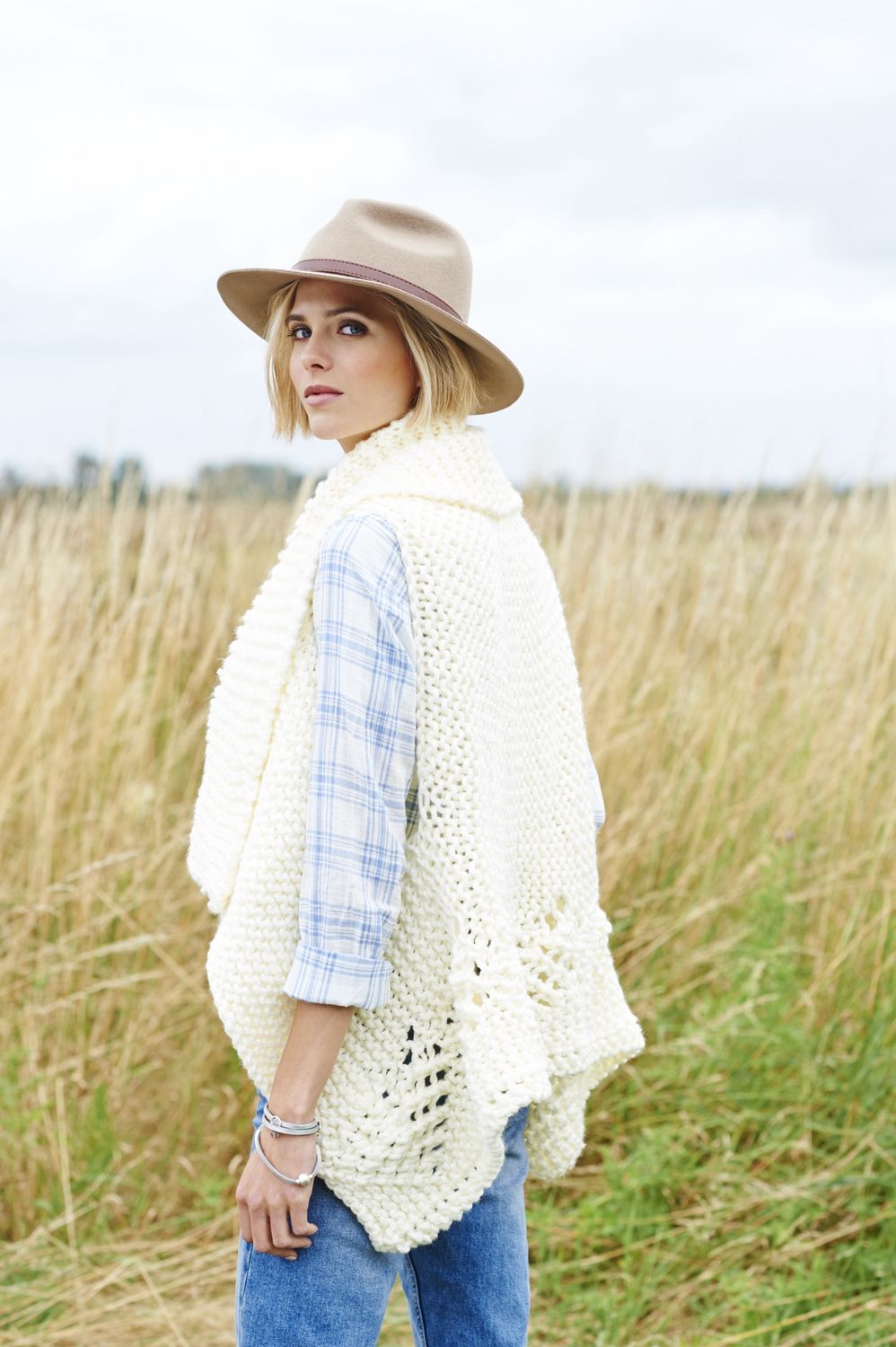 A woman is wearing a cream knitted waistcoat.