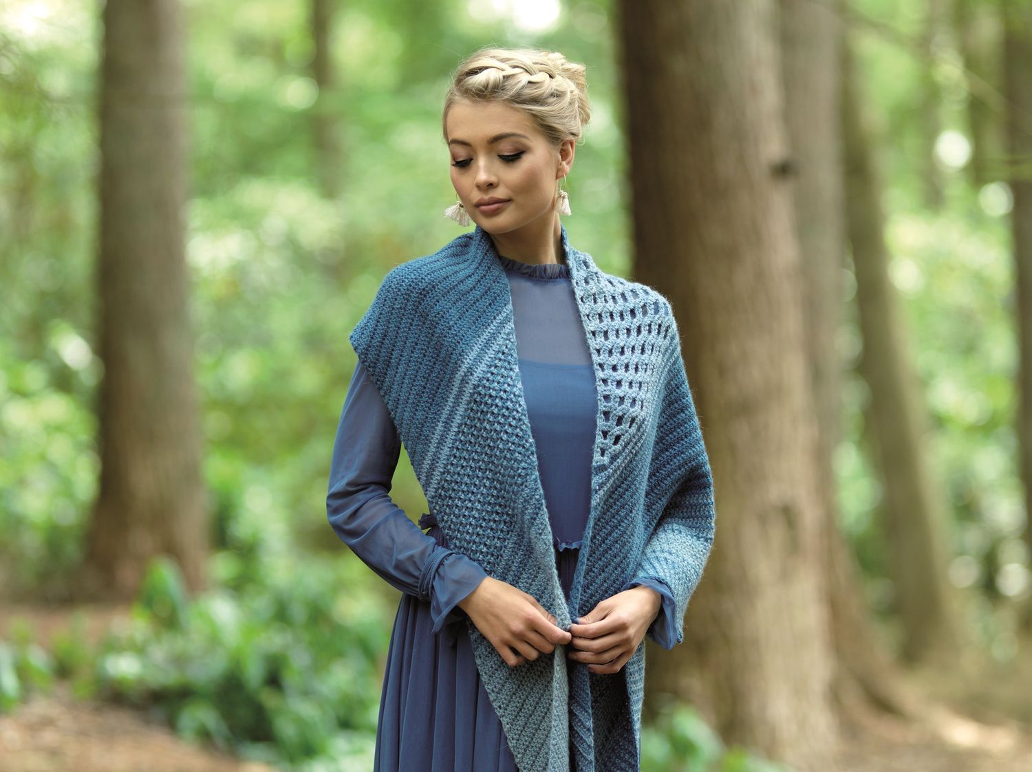 A woman is wearing a blue crocheted shawl.