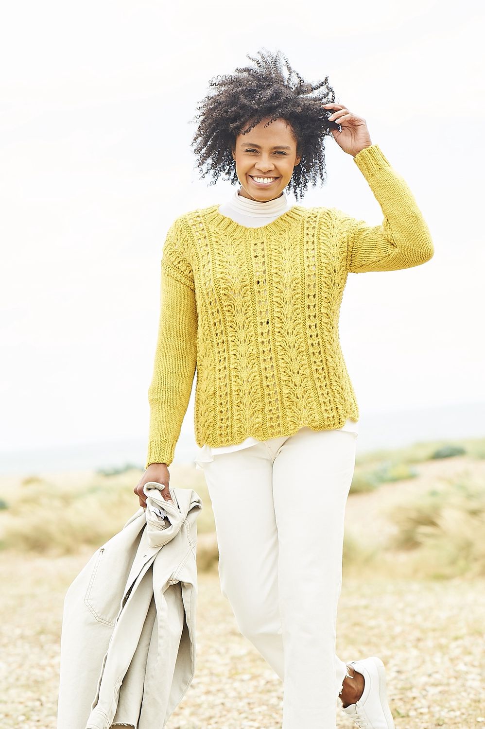 A woman is wearing a yellow lacy knitted sweater.