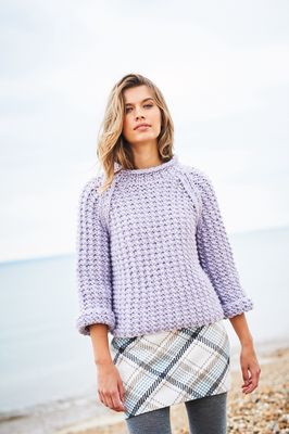 A woman is wearing a pale purple knitted sweater.