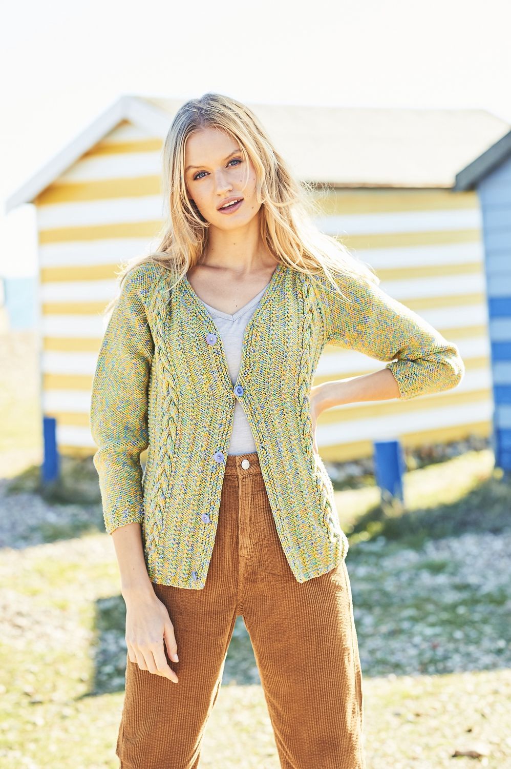 A woman is wearing a green cable knit cardigan.