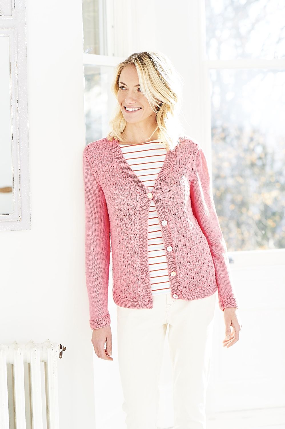 A woman is wearing a pink knitted cardigan.
