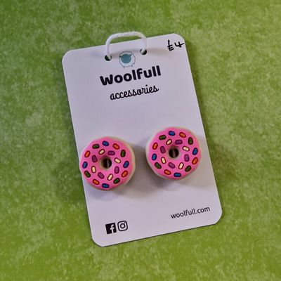 A green background with a pair of pink donut shaped point protectors mounted on a white card.