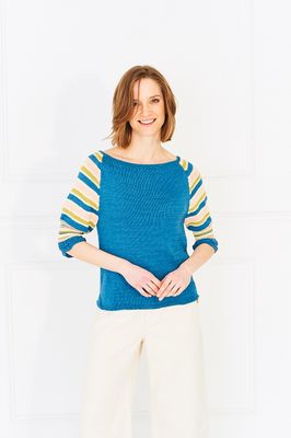 A woman is wearing a knitted sweater in blue, peach, green and cream.