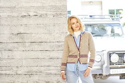 A woman is wearing a beige knitted cardigan.