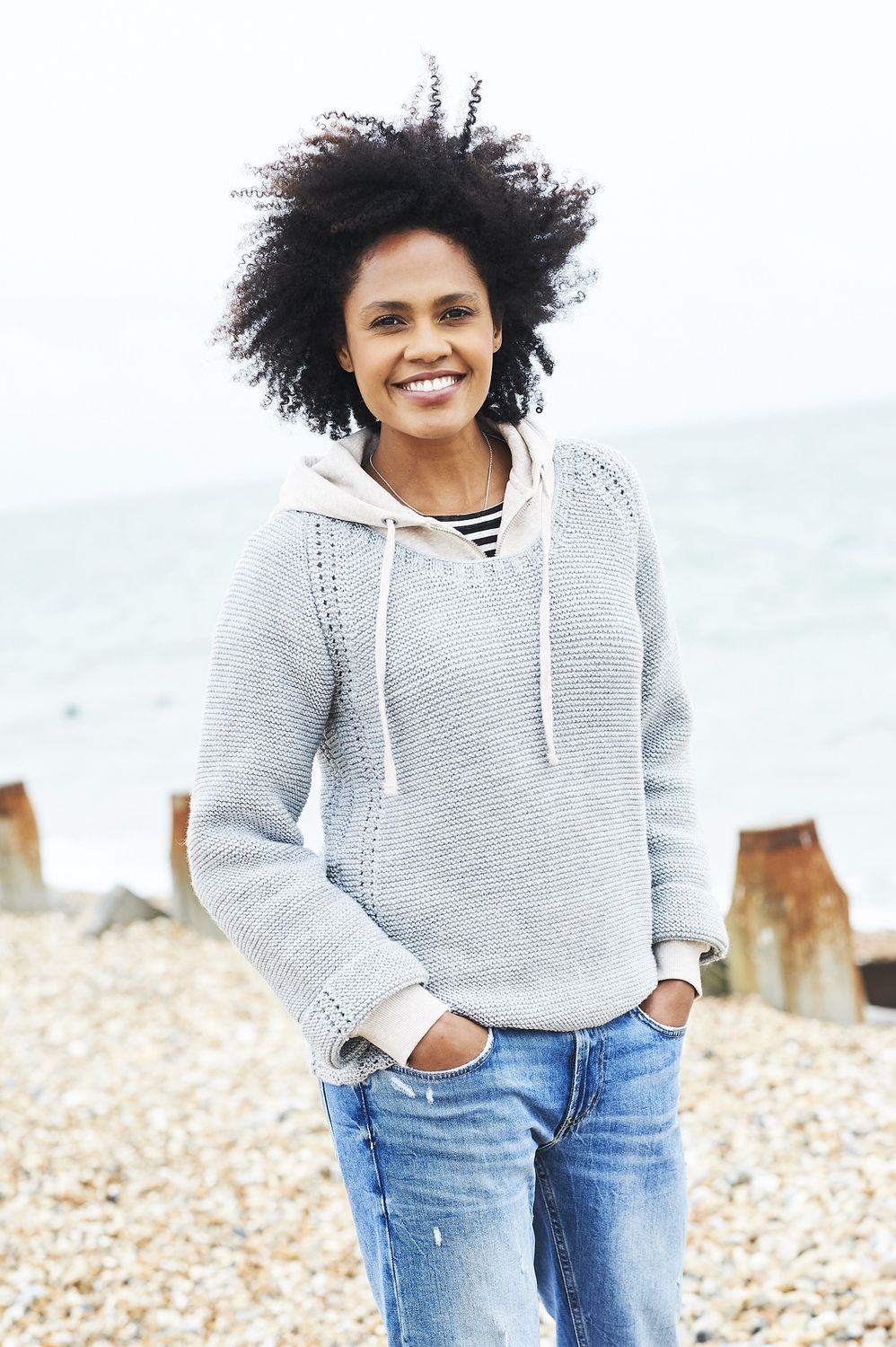 A woman is wearing a pale grey knitted sweater.