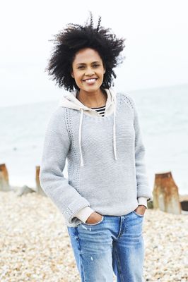 A woman is wearing a pale grey knitted sweater.
