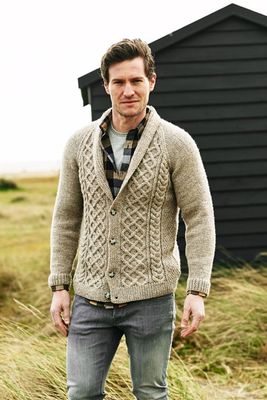 A man is wearing a beige cardigan with a cable design on the front.