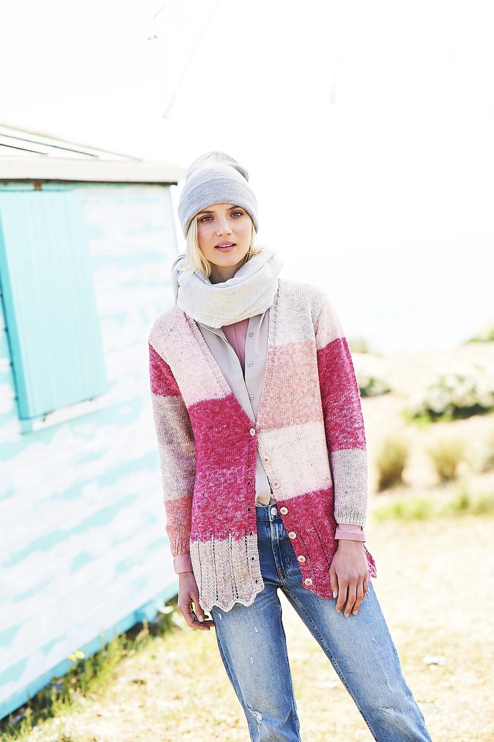 A woman is wearing a knitted cardigan in pink and cream stripes.