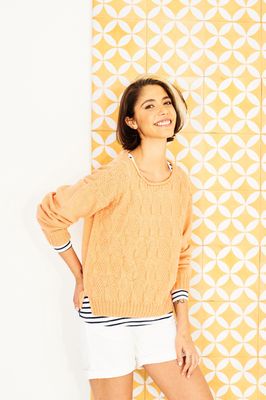 A woman is wearing a peach knitted sweater.