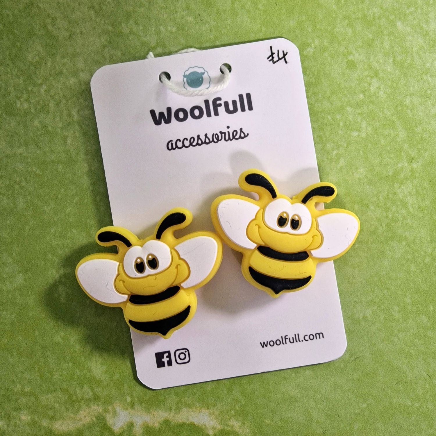 A green background with a pair of bumble bee shaped point protectors mounted on a white card.