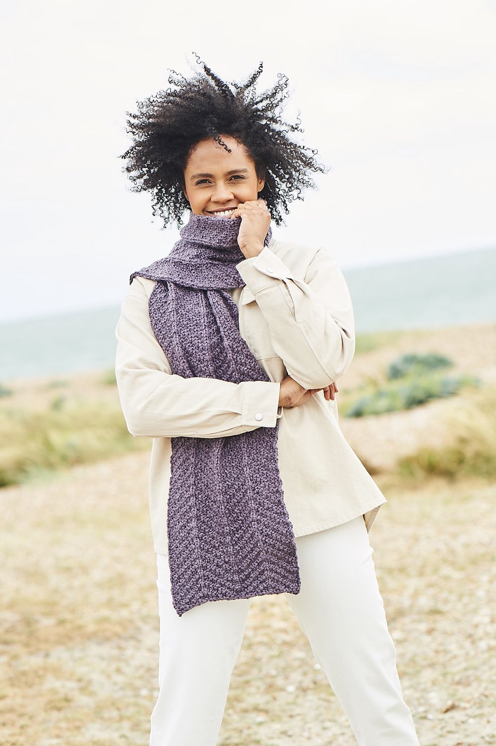 A woman is wearing a purple knitted scarf.