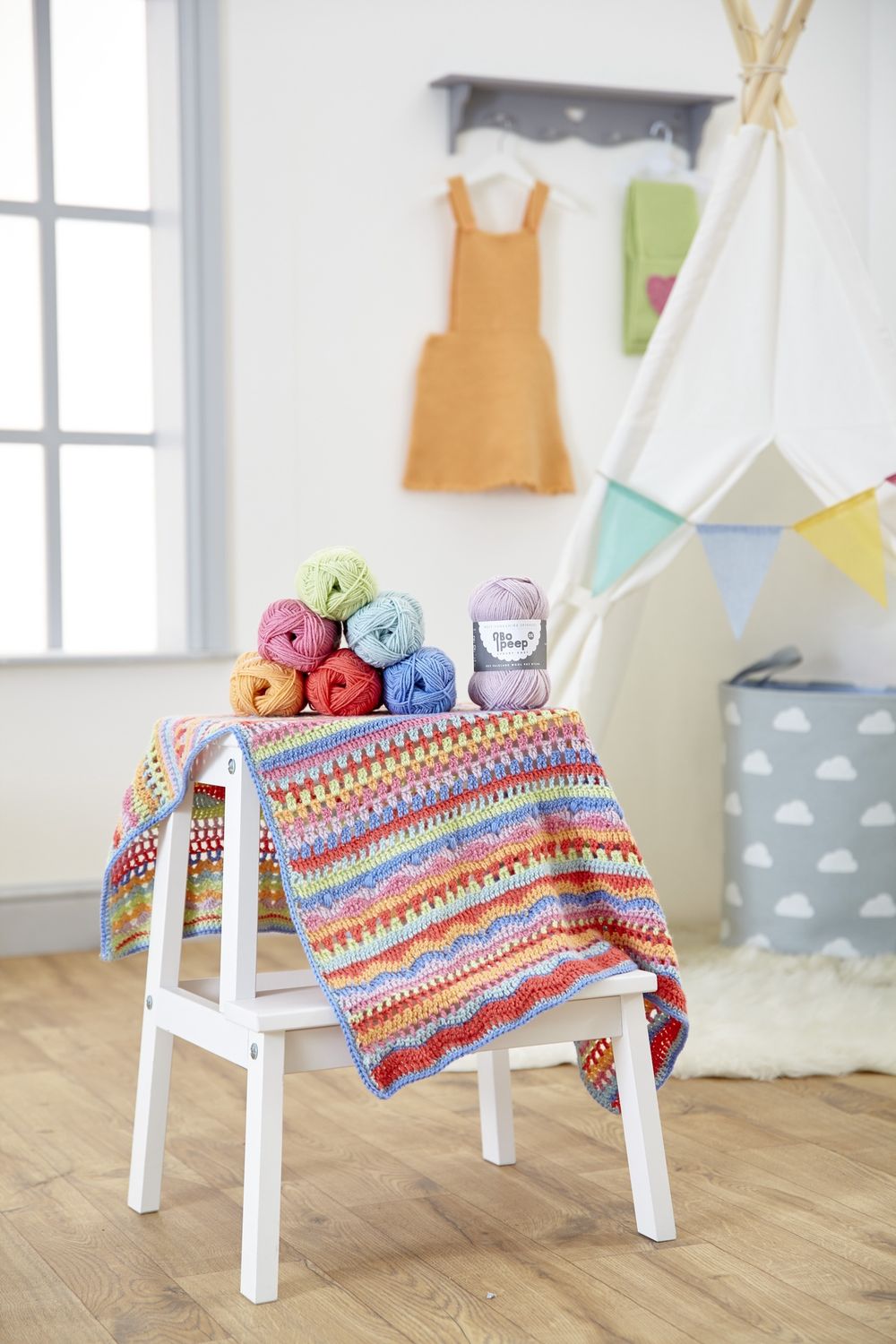 A crocheted blanket in red, orange, green, blue, pink and purple.