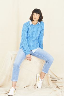 A woman is wearing a blue cable knit sweater.
