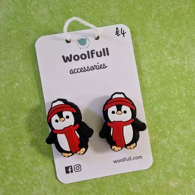 A green background with a pair of penguin shaped point protectors mounted on a white card.