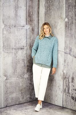A woman is wearing a blue cable knit sweater.