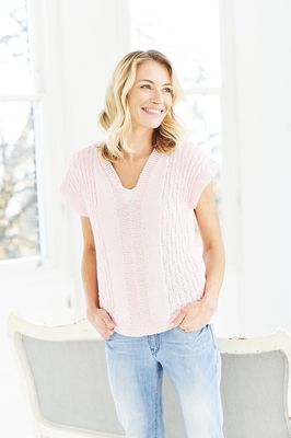 A woman is wearing a pale pink knitted top.