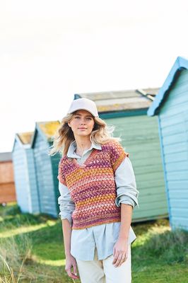 A woman is wearing a knitted top in shades of pink, purple and yellow.