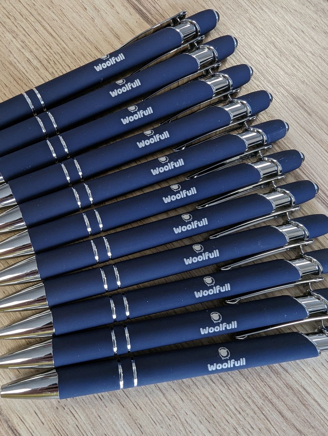 A bundle of Woolfull pens on a wooden background.