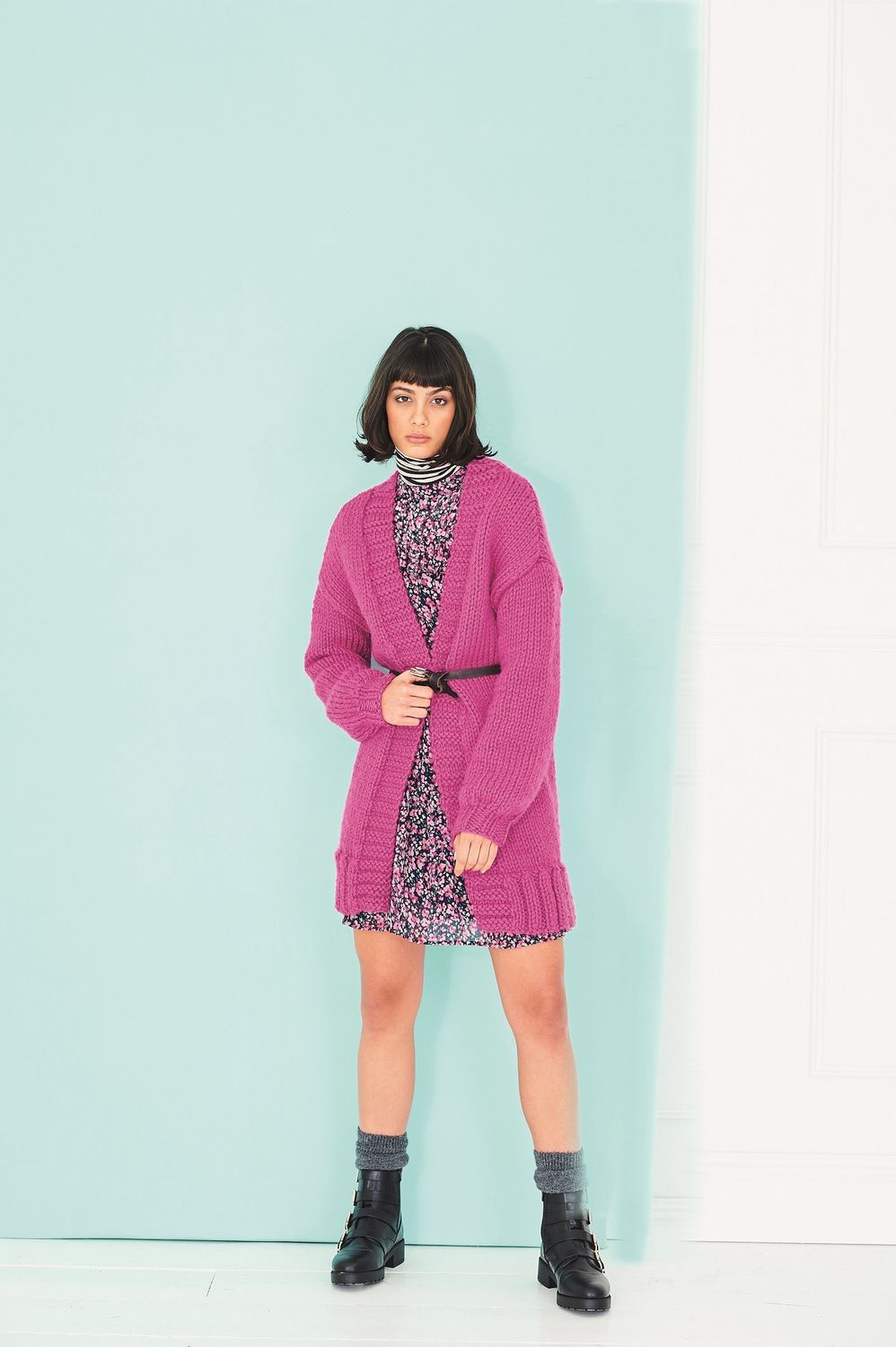 A woman is wearing a bright pink knitted cardigan.