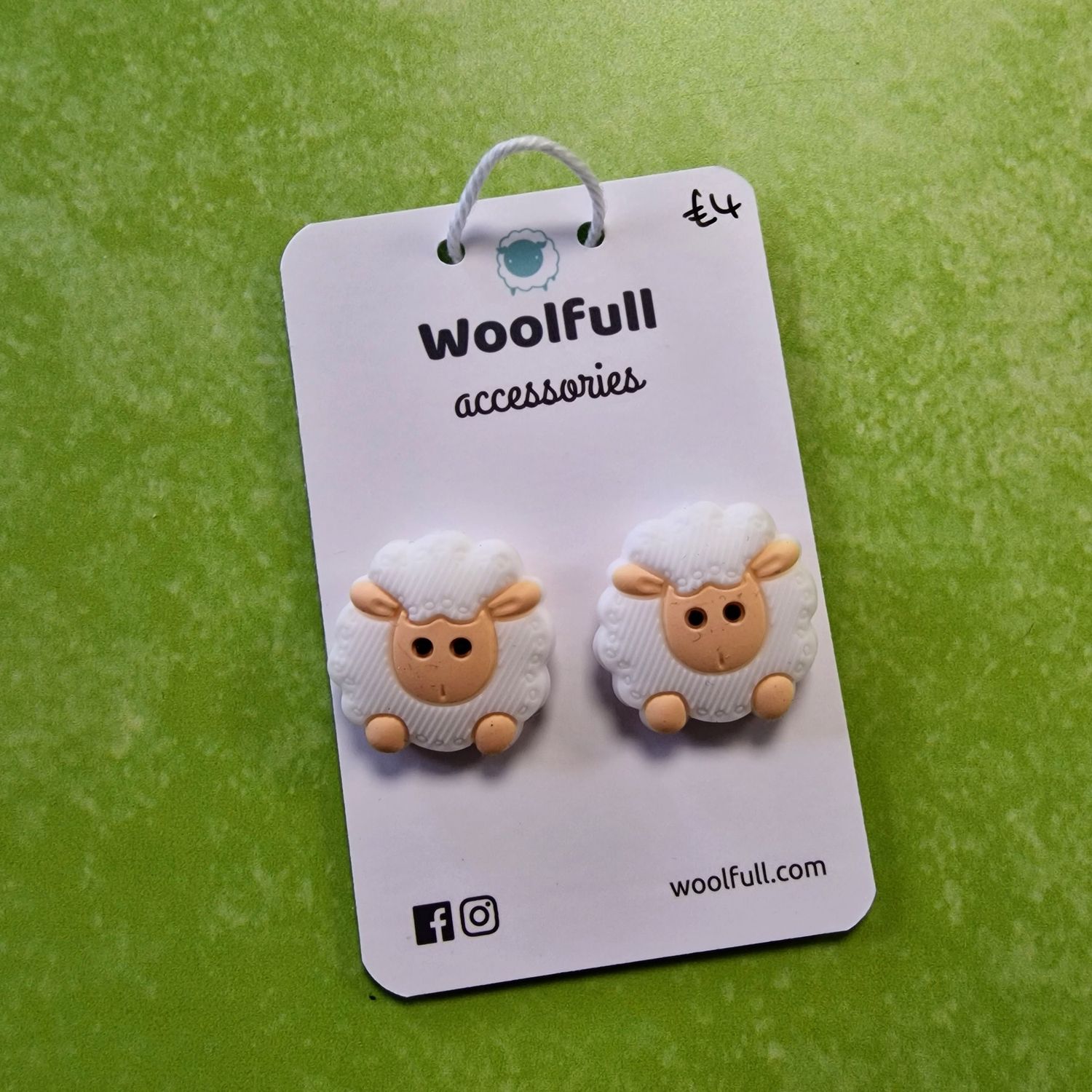 A green background with a pair of sheep shaped point protectors mounted on a white card.