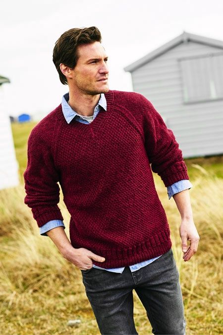 A man is wearing a dark red sweater with a moss stitch front.